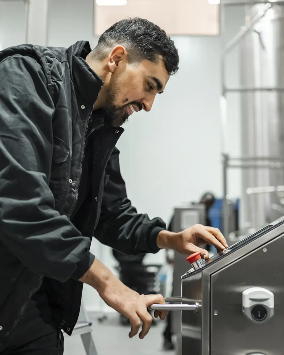 Un opérateur règle un équipement de contrôle industriel en acier inoxydable.