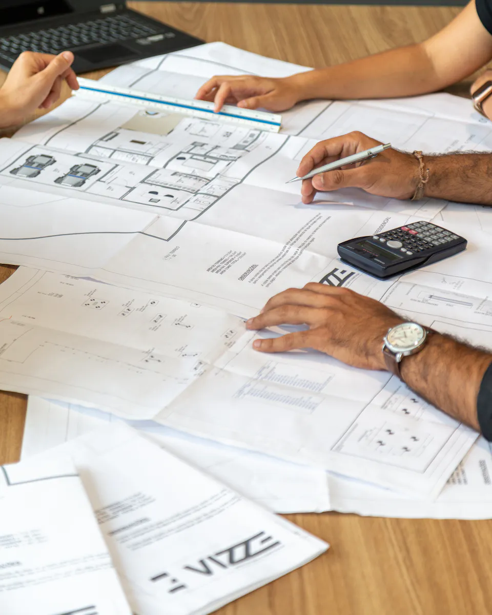 Des experts examinent des documents techniques autour d’une table de travail.